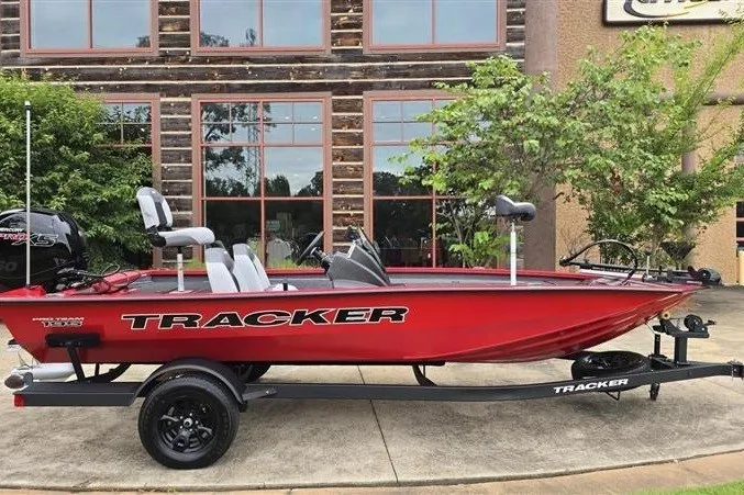 The Image of Red 2027 Tracker Pro Team 195 boat on trailer, parked outside a building. - 0