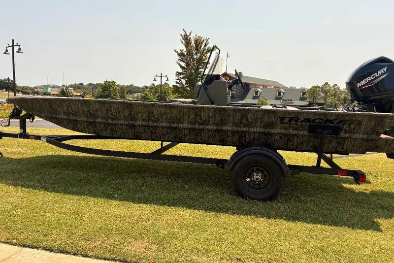 The Image of 2027 Tracker Grizzly 1860 CC boat on trailer, parked on grass, with Mercury engine. - 0