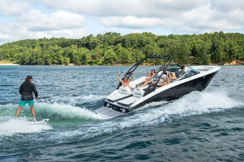 Slide: The Image of Manufacturer Provided Image: 2026 Regal LS6 Surf boat on lake, people enjoying watersports, lush forest background. - 1