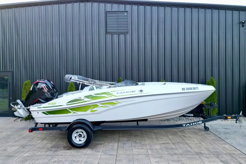 Slide: The Image of 2022 Tahoe T18 boat on trailer, parked outdoors near a metal building. - 17