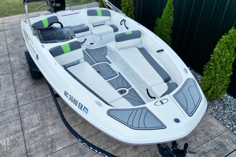 Slide: The Image of 2022 Tahoe T18 boat with sleek design, white and gray seating, parked on a paved surface. - 11