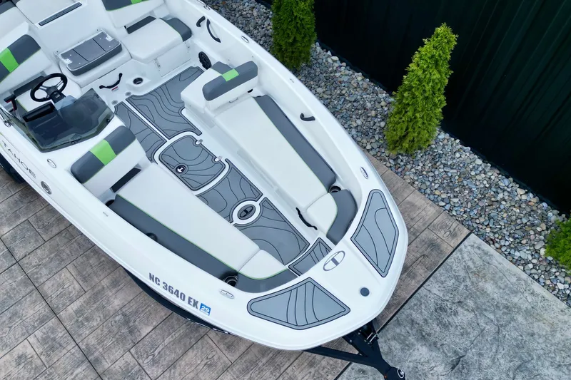Slide: The Image of 2022 Tahoe T18 boat with sleek design, gray and green seating, parked on stone pavement. - 12