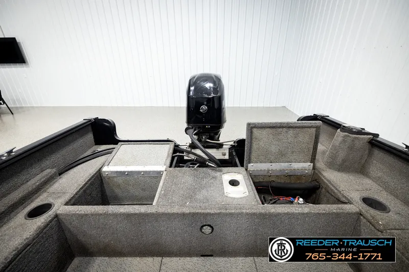 Slide: The Image of 2017 Lund 1650 Rebel XS SS boat interior with motor, storage compartments, and carpeted flooring. - 17