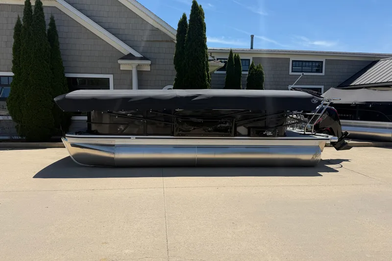 Slide: The Image of 2025 Crest Classic 200 pontoon boat with cover, parked outdoors. - 3