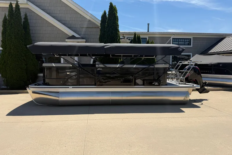 Slide: The Image of 2025 Crest Classic 200 pontoon boat with canopy, parked outdoors on a sunny day. - 2