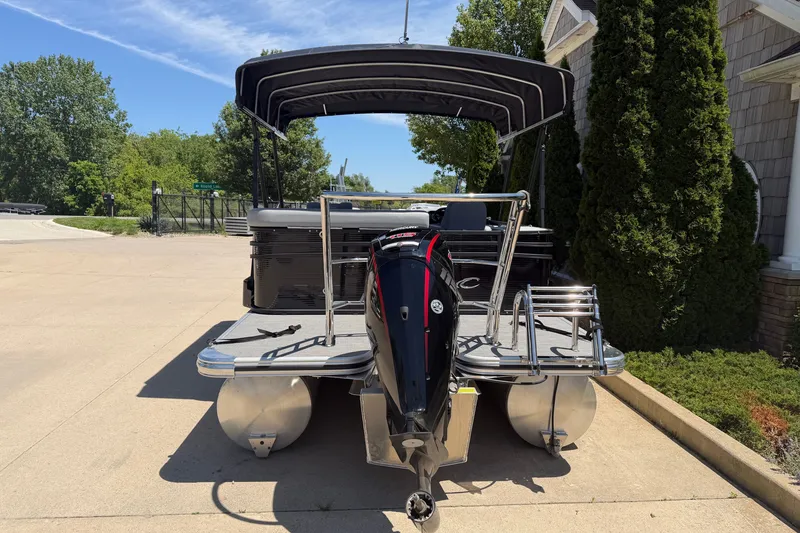 Slide: The Image of 2025 Crest Classic 200 pontoon boat with canopy and outboard motor on driveway. - 18