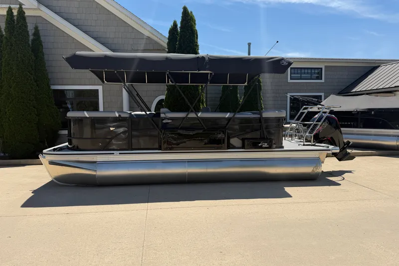 Slide: The Image of 2025 Crest Classic 200 pontoon boat with canopy, parked outdoors on a sunny day. - 1