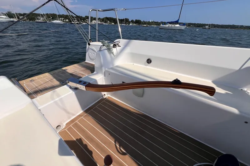 Slide: The Image of 2023 J Boats J/9 sailboat cockpit with wooden tiller, docked on calm water. - 16