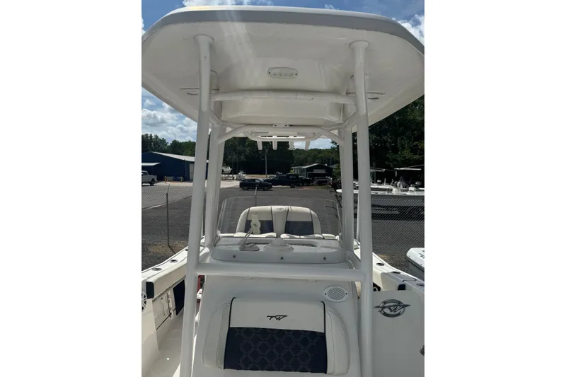 Slide: The Image of 2021 Tidewater 220 LXF boat interior with T-top and seating, parked outdoors. - 3
