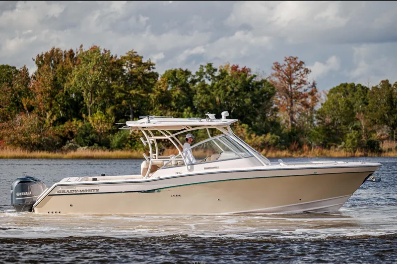 Slide: The Image of 2013 Grady-White Freedom 335 boat cruising on a scenic lake with lush trees. - 2