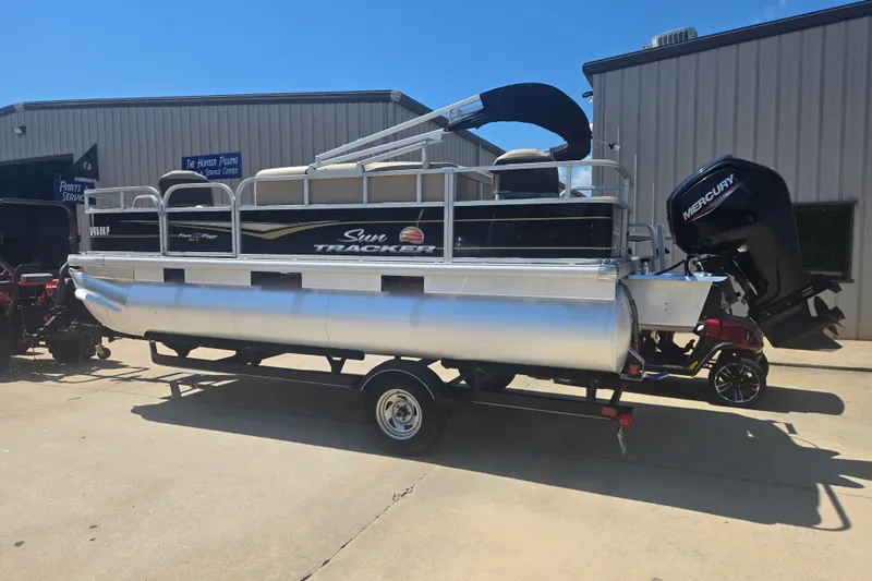 Slide: The Image of 2021 Sun Tracker Bass Buggy 18 DLX pontoon boat on trailer, parked outside service center. - 21