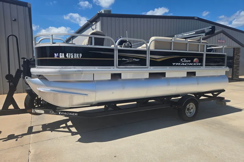 The Image of 2021 Sun Tracker Bass Buggy 18 DLX pontoon boat on trailer, parked outdoors. - 1