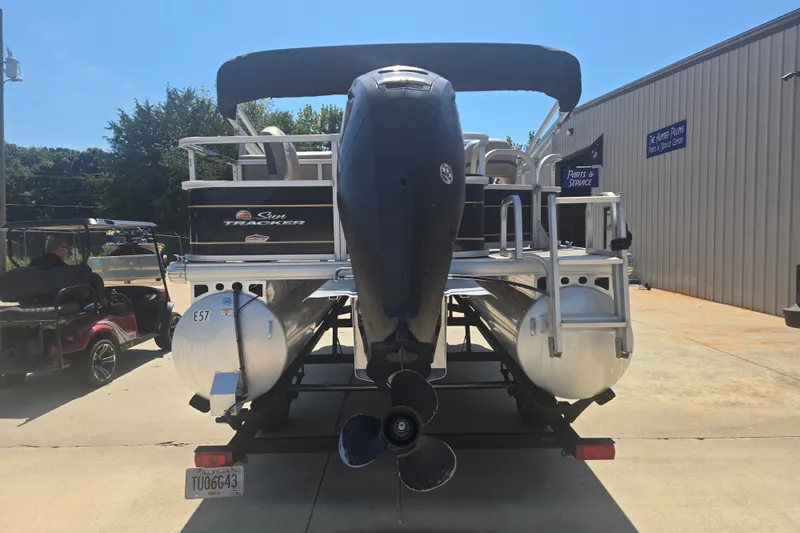 Slide: The Image of 2021 Sun Tracker Bass Buggy 18 DLX pontoon boat with outboard motor, parked outdoors. - 19