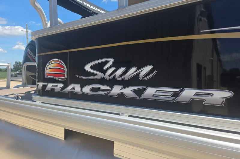 Slide: The Image of 2021 Sun Tracker Bass Buggy 18 DLX logo on boat exterior under sunny sky. - 16