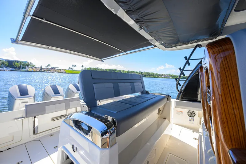Slide: The Image of 2024 Boston Whaler 42 OUTRAGE boat interior with seating and canopy, overlooking serene water. - 57