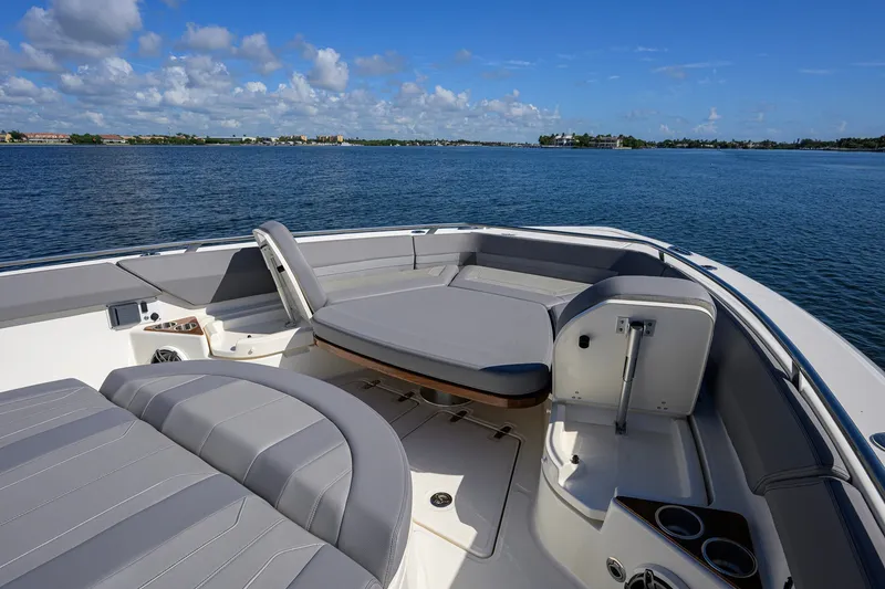 Slide: The Image of 2024 Boston Whaler 42 OUTRAGE boat interior with cushioned seating on calm water. - 10