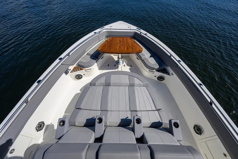 Slide: The Image of 2024 Boston Whaler 42 OUTRAGE boat interior with luxurious seating and wooden table on calm water. - 14