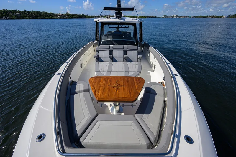 Slide: The Image of 2024 Boston Whaler 42 OUTRAGE boat with luxurious seating and wooden table on open water. - 15