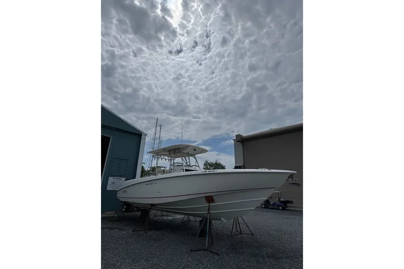 The Image of 2005 Boston Whaler Outrage 320 boat on stands under cloudy sky. - 0