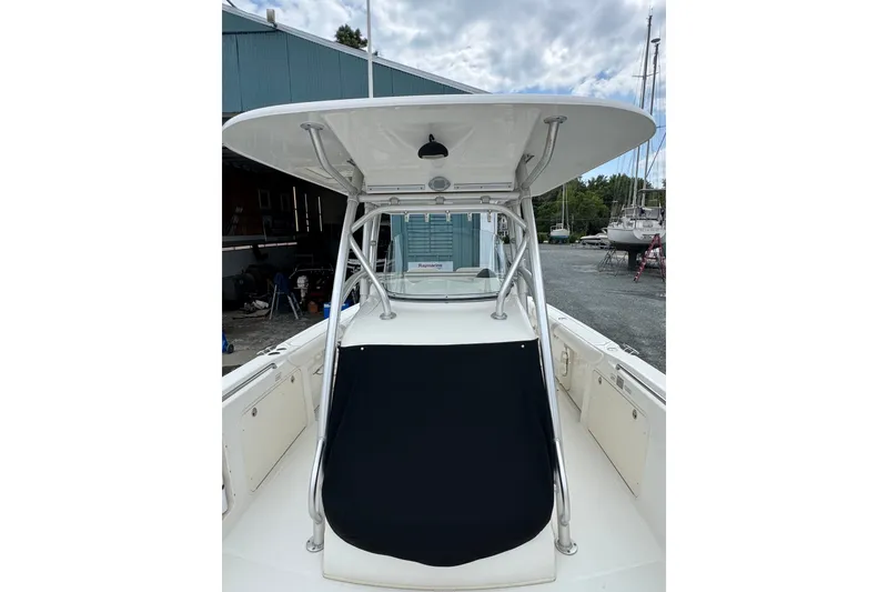 Slide: The Image of 2005 Boston Whaler Outrage 320 boat with T-top and console, docked outdoors. - 4
