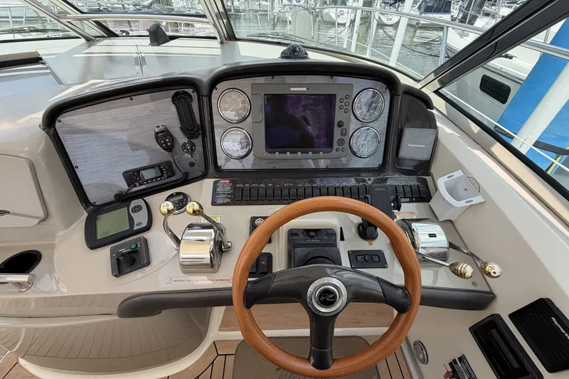 Slide: The Image of 2004 Sea Ray 390 Sundancer helm with navigation controls and wooden steering wheel. - 14