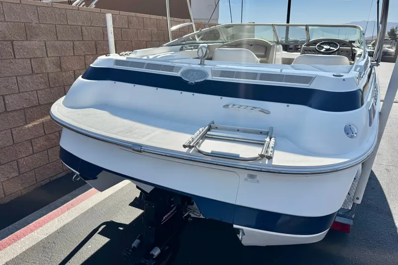 Slide: The Image of 2001 Cobalt 232 boat, rear view, white and blue design, parked on a trailer. - 6