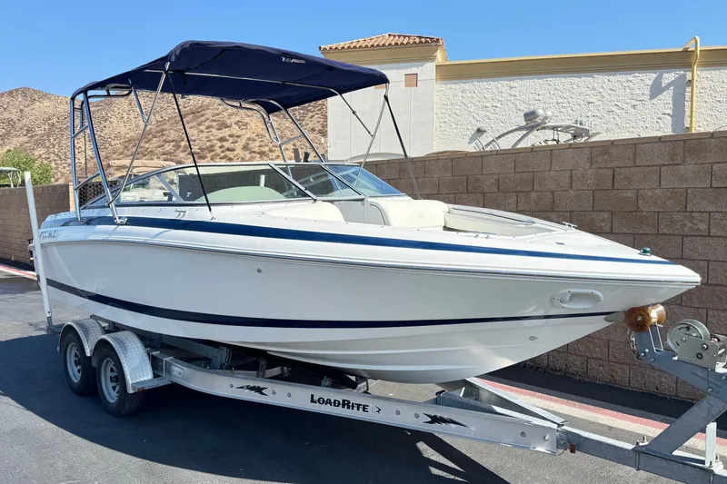 Slide: The Image of 2001 Cobalt 232 boat on trailer, parked outdoors with hills in background. - 1