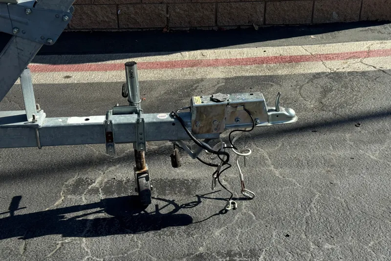 Slide: The Image of Trailer hitch of a 2001 Cobalt 232 on asphalt, showing wiring and metal components. - 33