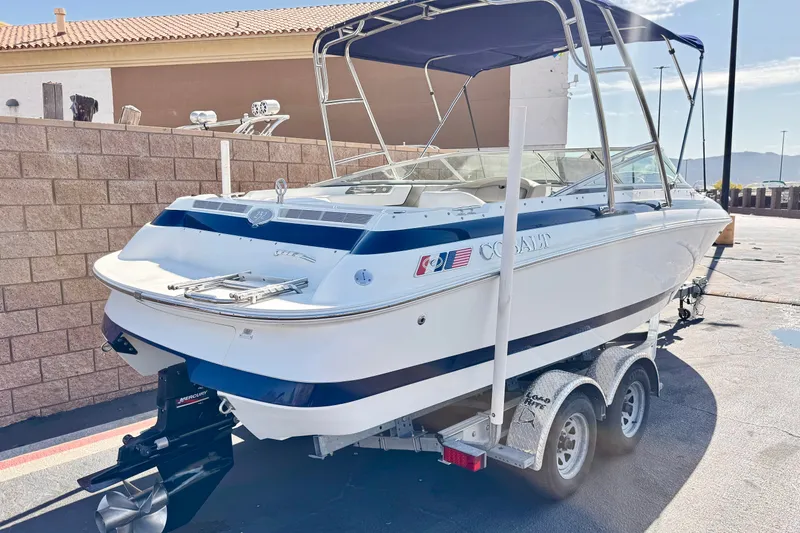Slide: The Image of 2001 Cobalt 232 boat on trailer, parked outdoors, with blue and white design. - 5