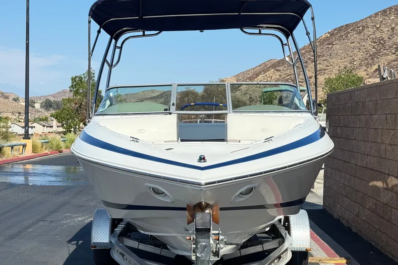 Slide: The Image of 2001 Cobalt 232 boat on trailer, parked outdoors with scenic mountain backdrop. - 2