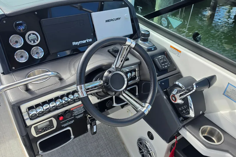 Slide: The Image of 2023 Formula 290 Bowrider helm with steering wheel, Raymarine display, and Mercury controls. - 19