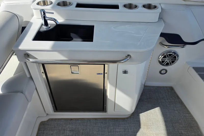 Slide: The Image of 2023 Formula 290 Bowrider boat kitchenette with sink, stainless steel fridge, and cup holders. - 28