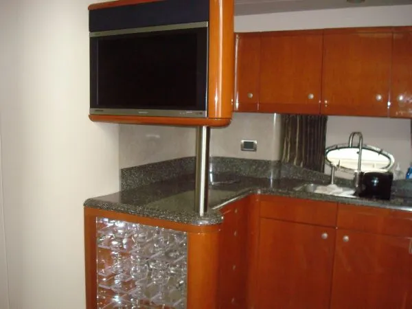 Slide: The Image of The interior of the 2006 Formula 48 Yacht features an elegant kitchen with wood cabinets and granite surfaces. - 25