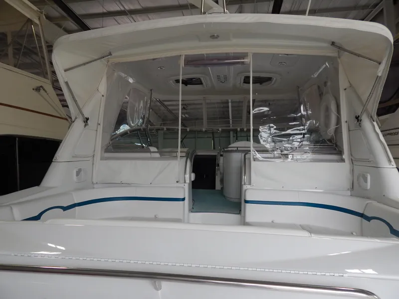 Slide: The Image of The rear of a white yacht with a covered cockpit and clear plastic curtains. - 38