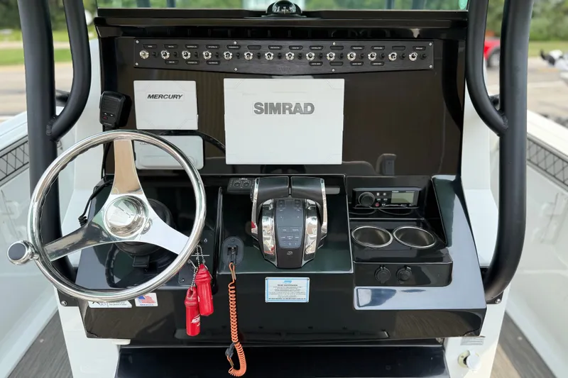 Slide: The Image of 2022 Wellcraft 262 Fisherman boat dashboard with steering wheel, Simrad display, and controls. - 5