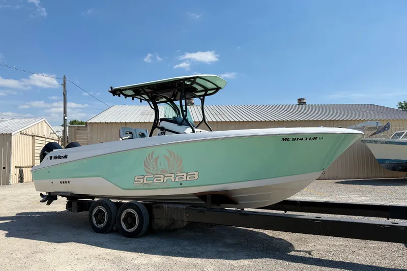 Slide: The Image of 2022 Wellcraft 262 Fisherman boat on trailer, mint green hull, parked outdoors. - 1