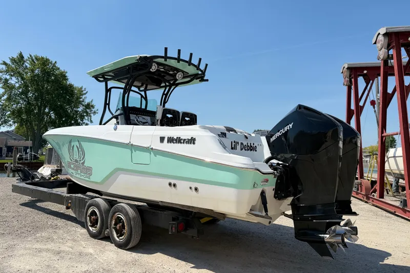 Slide: The Image of 2022 Wellcraft 262 Fisherman boat on trailer, featuring dual Mercury engines. - 23