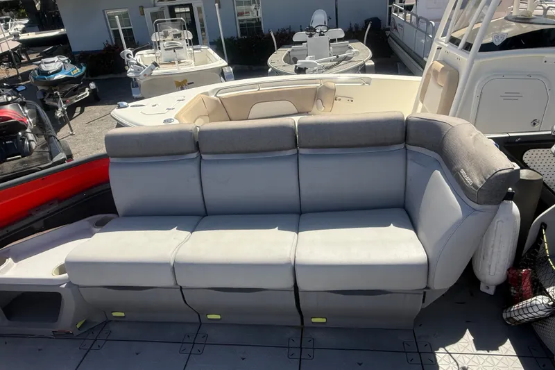 Slide: The Image of 2023 Sea-Doo Switch Cruise 21 boat with comfortable gray seating in a marina setting. - 17