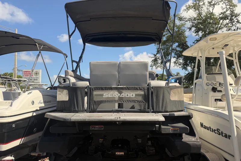 Slide: The Image of 2023 Sea-Doo Switch Cruise 21 pontoon boat with canopy, docked between other boats. - 3