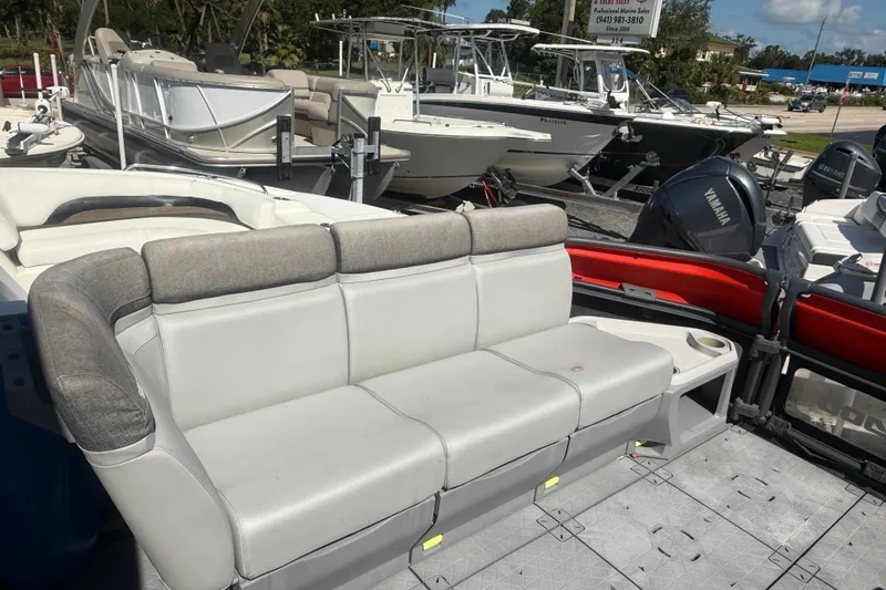 Slide: The Image of 2023 Sea-Doo Switch Cruise 21 pontoon boat with comfortable seating, docked among other boats. - 16