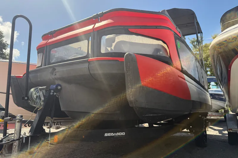 Slide: The Image of 2023 Sea-Doo Switch Cruise 21 on trailer, red and black design, sunny day. - 2