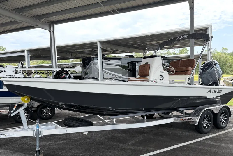 The Image of Avid 21 Fusion 2027 boat on trailer under covered parking, featuring sleek design and modern equipment. - 0
