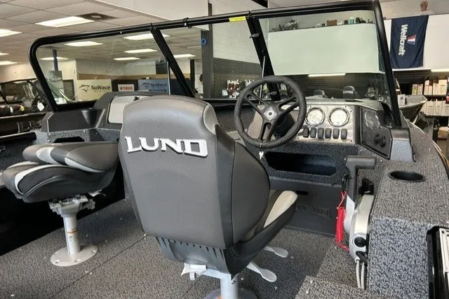 Slide: The Image of 2027 Lund 1800 Adventure Sport boat interior with steering wheel and seating. - 6