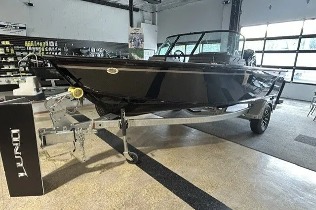 Slide: The Image of 2027 Lund 1800 Adventure Sport boat displayed in a showroom on a trailer. - 2