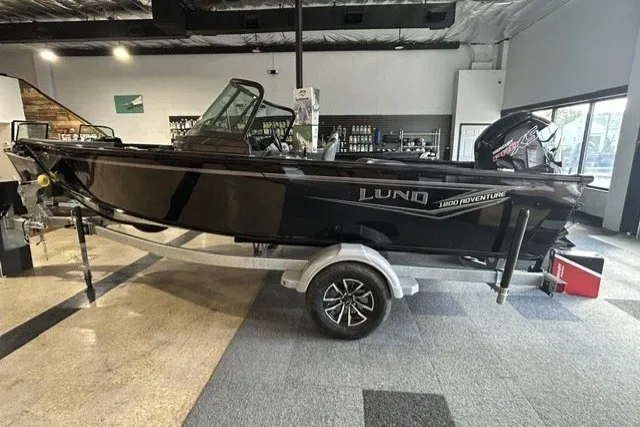 The Image of 2027 Lund 1800 Adventure Sport boat displayed indoors on a trailer. - 1