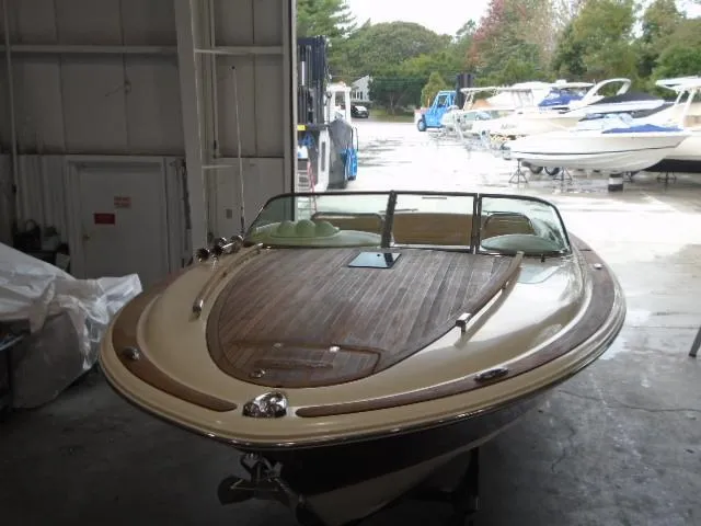 Slide: The Image of A 2012 Chris-Craft Corsair 28 in a warehouse. It features a sleek wooden deck. - 3