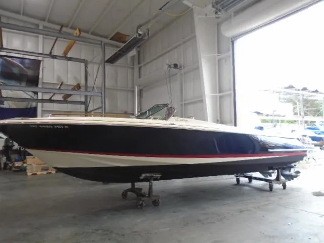 The Image of A 2012 Chris-Craft Corsair 28 is in a warehouse. The boat features an elegant, classic style. - 0