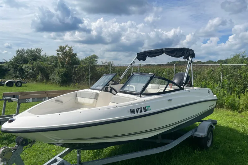 The Image of 2017 Bayliner 170 Bowrider boat on trailer, parked on grassy area under cloudy sky. - 0