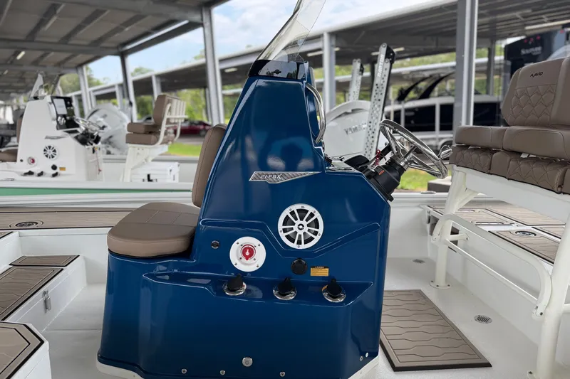 Slide: The Image of 2027 Avid 21 FSX boat interior with blue console and seating under a covered dock. - 16