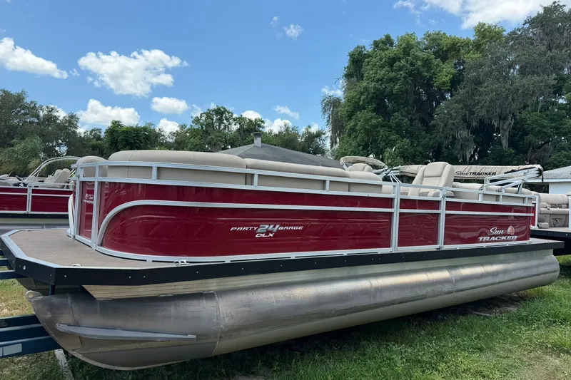 The Image of 2025 Sun Tracker Party Barge 24 DLX pontoon boat with red hull and beige interior. - 0